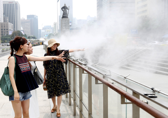 폭염이 계속된 20일 서울 광화문 광장에서 시민들이 물방울 분무 시설 옆을 지나며 더위를 식히고 있다. /연합뉴스