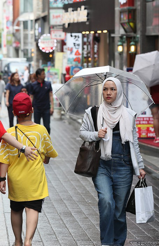 21일 서울 중구 명동을 찾은 무슬림 관광객이 우산을 쓴 채 가게를 살펴보고 있다. /연합뉴스