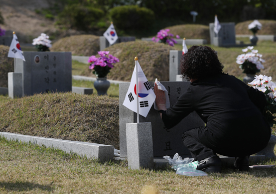 4.19 혁명 제58주년을 하루 앞둔 18일 서울 강북구 국립 4.19 민주묘지를 찾은 추모객이 묘비를 닦고 있다. /연합뉴스