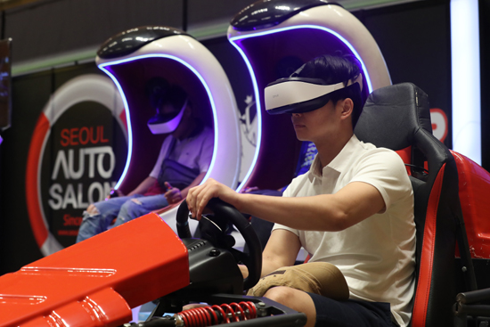 19일 서울 강남구 코엑스에서 열린 '2018 서울 오토살롱'에서 참관객들이 레이싱 VR시스템을 체험하고 있다. /연합뉴스