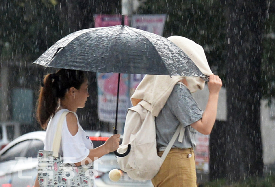 폭염이 계속된 28일 전주시 금암동 일대에 소나기가 내리자 시민들이 우산을 받고 신호등을 건너고 있다./이원철기자