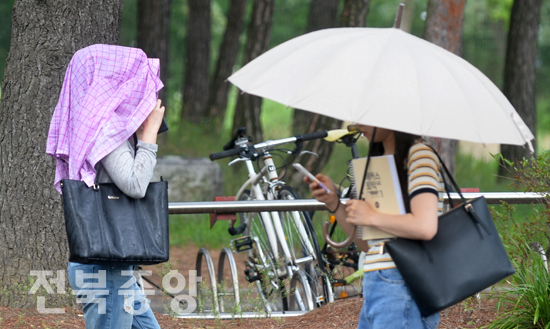 소나기가 내린 15일 전북대학교에서 한 학생이 우산 대신 웃옷으로 비를 피하며 서둘러 이동하고 있다./이원철기자