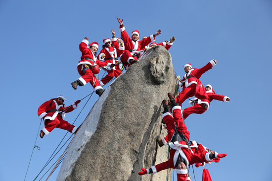 22일 서울 북한산 만경대에서 산타 복장을 한 쌩곰산악회와 멀티암벽산악회 대원들이 2020년 산악인들의 안전산행 기원과 다가오는 크리스마스를 기념한 퍼포먼스를 하고 있다. /연합뉴스