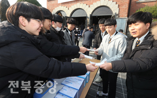 30일 전주신흥고등학교에서 열린 졸업식장 앞에서 학생들이 신종 코로나바이러스(우한폐렴) 확산 예방을 위해 마스크를 나눠주고 있다./이원철기자