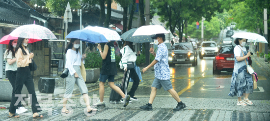 전북지역에 호우주의보가 내려진 5일 전주 한옥마을에서 관광객과 시민들이 갑자기 내린 소나기에 우산을 받고 서둘러 이동하고 있다./이원철기자