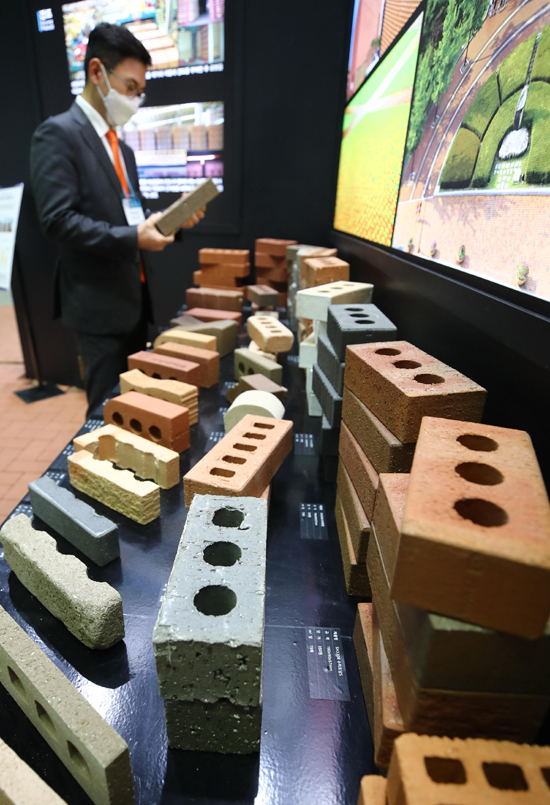 18일 서울 강남구 코엑스에서 개막한 '한국건축산업대전 2020'의 한 부스에서 관계자가 전시된 벽돌을 살펴보고 있다. /연합뉴스