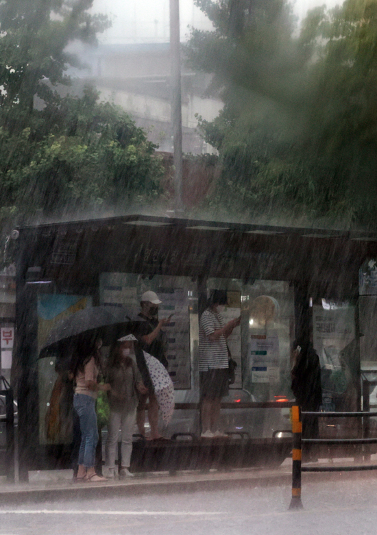 짧은 시간 강한 소나기가 내린 28일 오후 시민들이 버스정류장에서 갑자기 내린 비를 피하고 있다. /연합뉴스