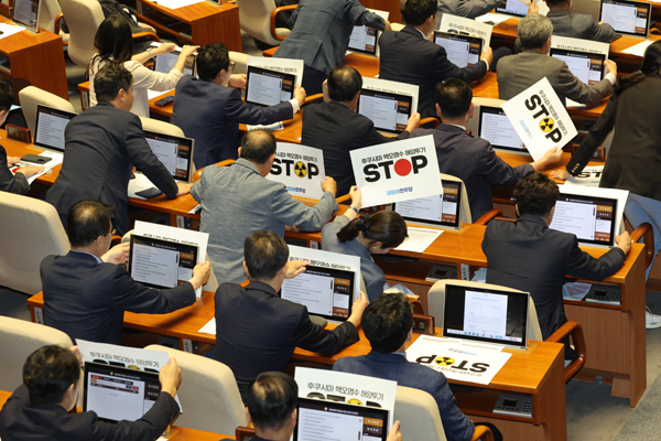 24일 오후 국회에서 열린 본회의에서 더불어민주당 의원들이 일본 후쿠시마 핵오염수 해양투기를 반대하는 손팻말을 모니터에 붙이고 있다. /연합뉴스
