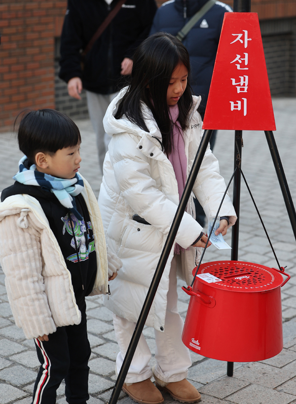 3일 오후 도심 거리에서 한 어린이가 구세군 자선냄비에 성금을 넣고 있다. /연합뉴스
