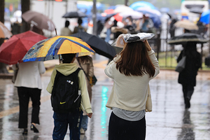 전국 곳곳에 비가 내린 15일 한 시민이 포장된 의류로 비를 막으며 이동하고 있다. /연합뉴스